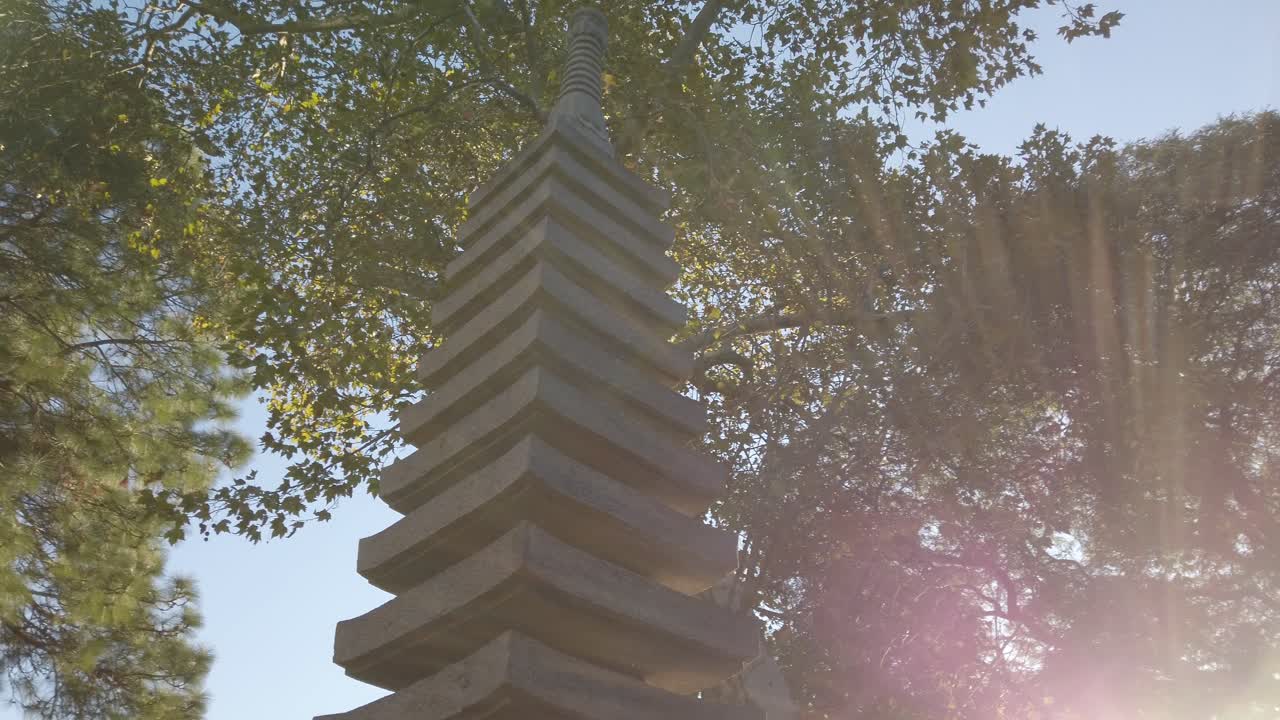 Panorering til venstre, lysglimt. Solstråler i den gyldne time over en japansk stenpagode.