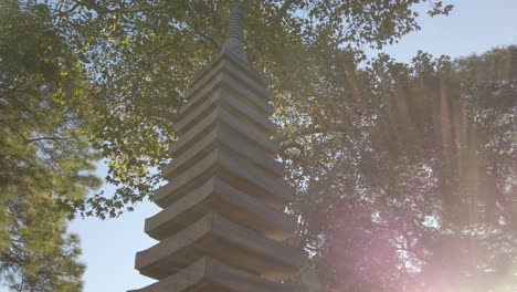 pan left flare golden hour sunbeams over stone japanese pagoda