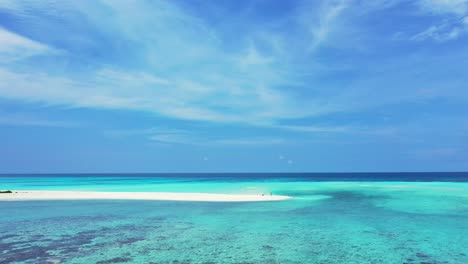 peaceful seascape with calm clear water of turquoise lagoon, coral reef patterns under water and blue sky with white clouds in maldives