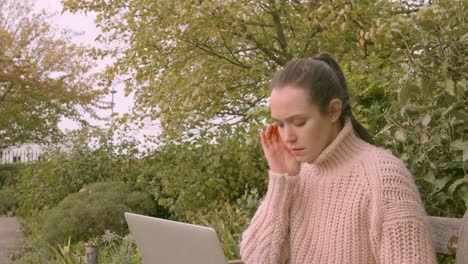 female working on a laptop in a park working hard and feeling confused