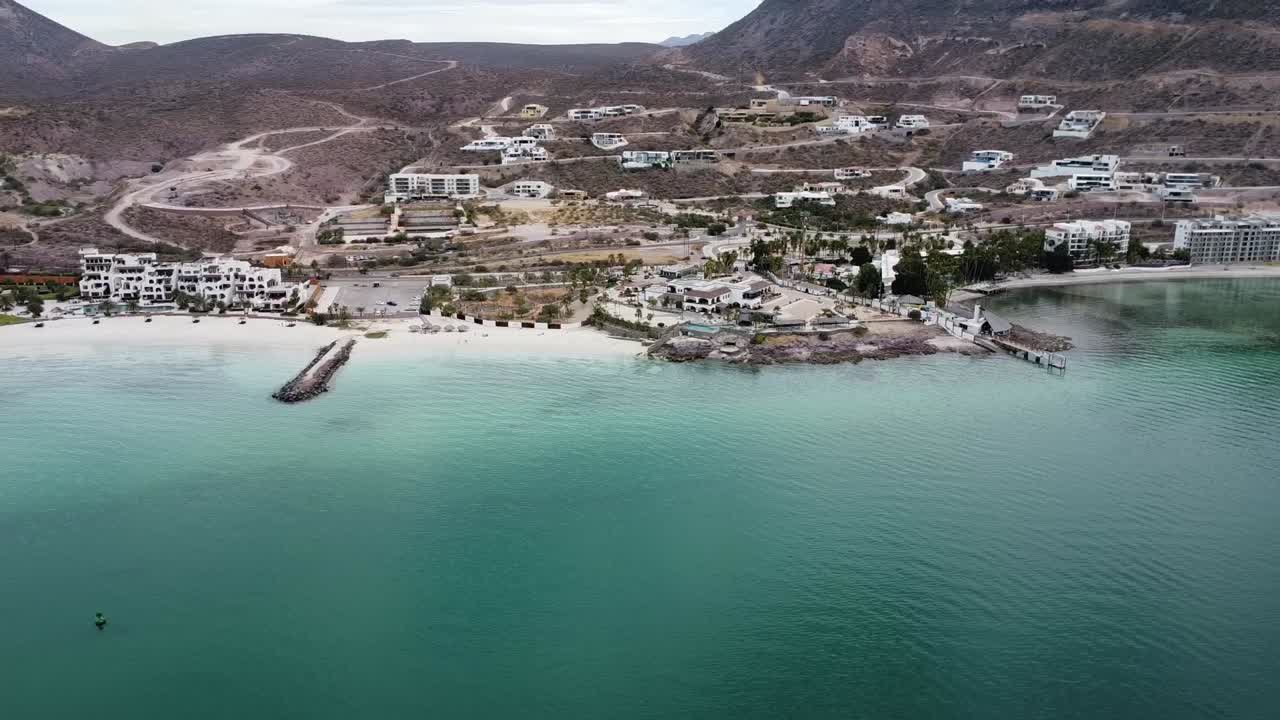 바하 캘리포니아 주 라파즈에 있는 플라야 카이만시토 (plaja caimancito) 와 라콘차 (la concha) 의 공중 촬영으로, 조용한 칠색 물과 해안 휴양지를 보여준다.