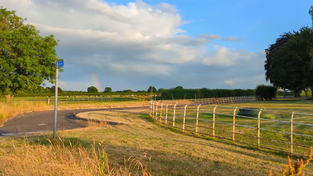 Dia de verão no campo em Lymm, Cheshire, com vista para terras agrícolas, árvores e um arco-íris ao longe