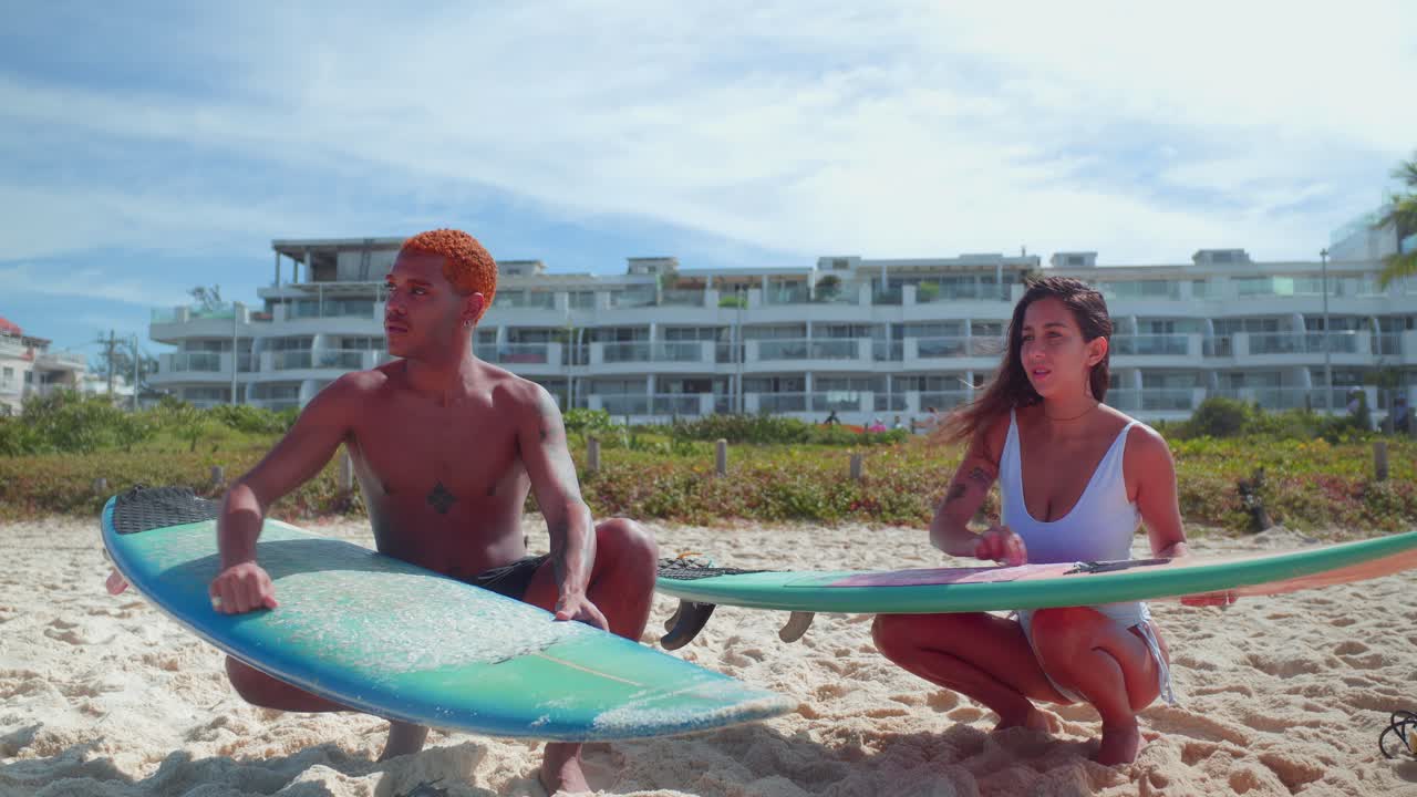 Couple preparing surfboards on a sunny beach