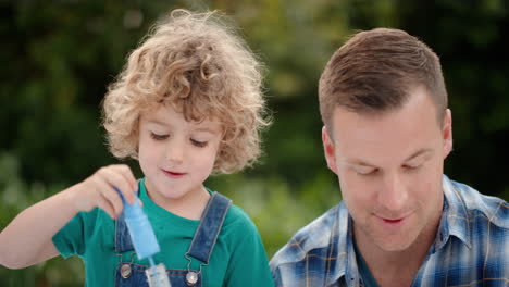 Vater-Und-Sohn-Blasen-Gemeinsam-Seifenblasen-Im-Sonnigen-Park.-Süßer-Kleiner-Junge,-Der-Spaß-Hat.-Vater-Spielt-Mit-Kind-Und-Genießt-Spielerisch-Den-Sommer-4k