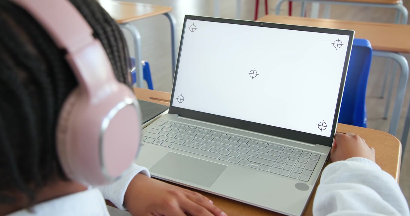 Male youth sitting at school using laptop with alignment marks, adjusting grip on edge, copy space