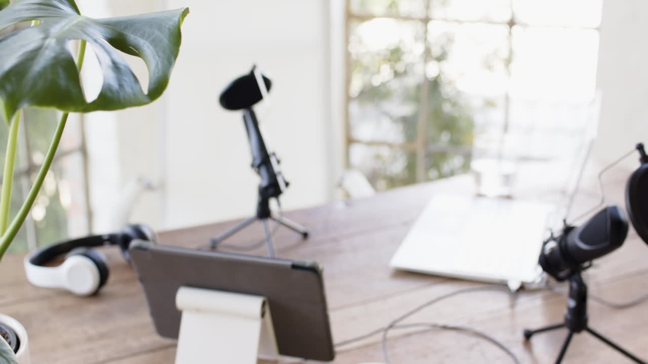 Podcast setup with microphone, tablet, and headphones on wooden table at home