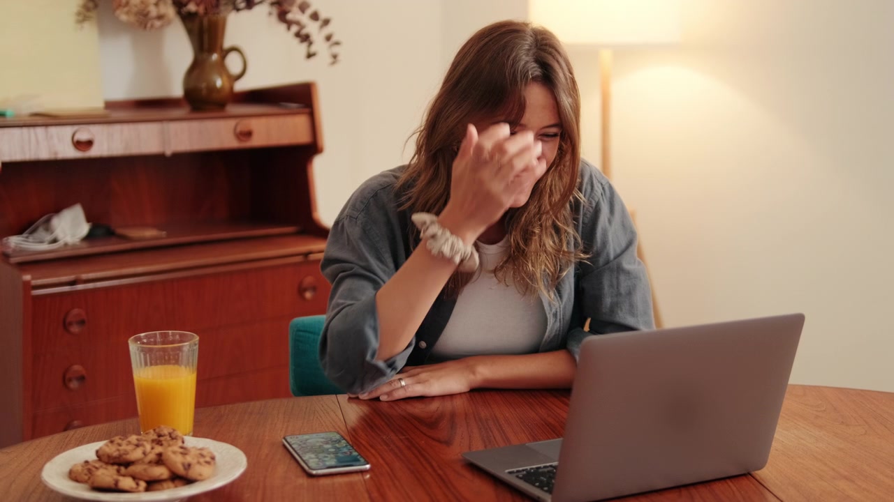 Donna felice che effettua una videochiamata sul portatile a casa