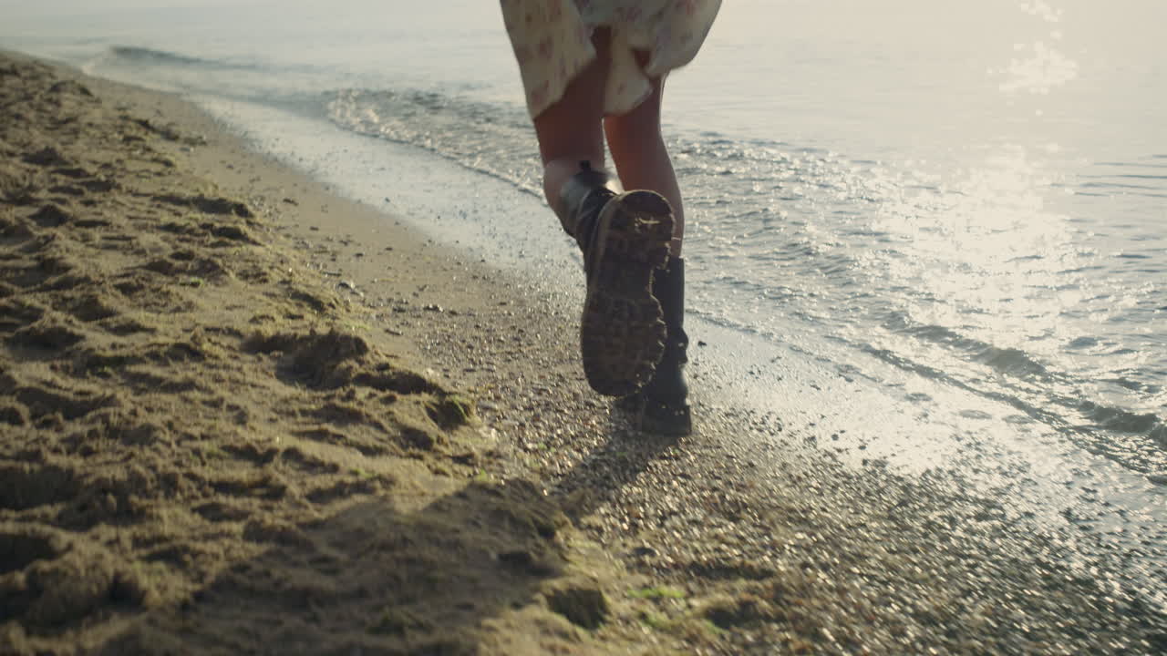 Gambe di donna alla moda con stivali che corrono sulla spiaggia. Ragazza allegra in posa davanti alla fotocamera.