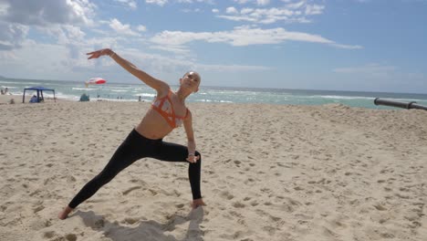 yoga en la playa de burleigh heads - yogui haciendo un ángulo lateral extendido para invertir la pose del guerrero en la playa de arena - costa dorada, qld, australia