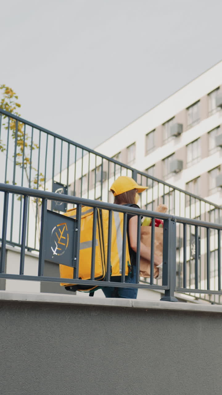 Delivery person carrying groceries near a building