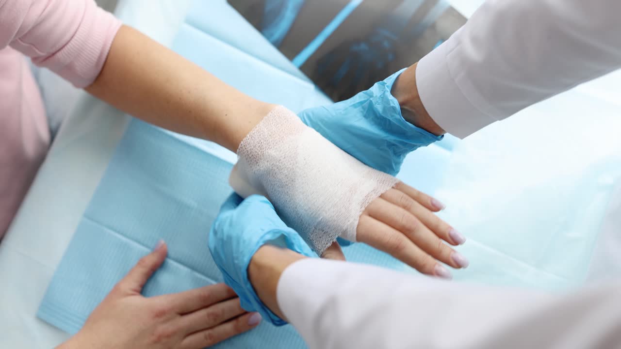 Médico enfaixando o braço ferido de paciente em clínica, close-up (filme 4k)
