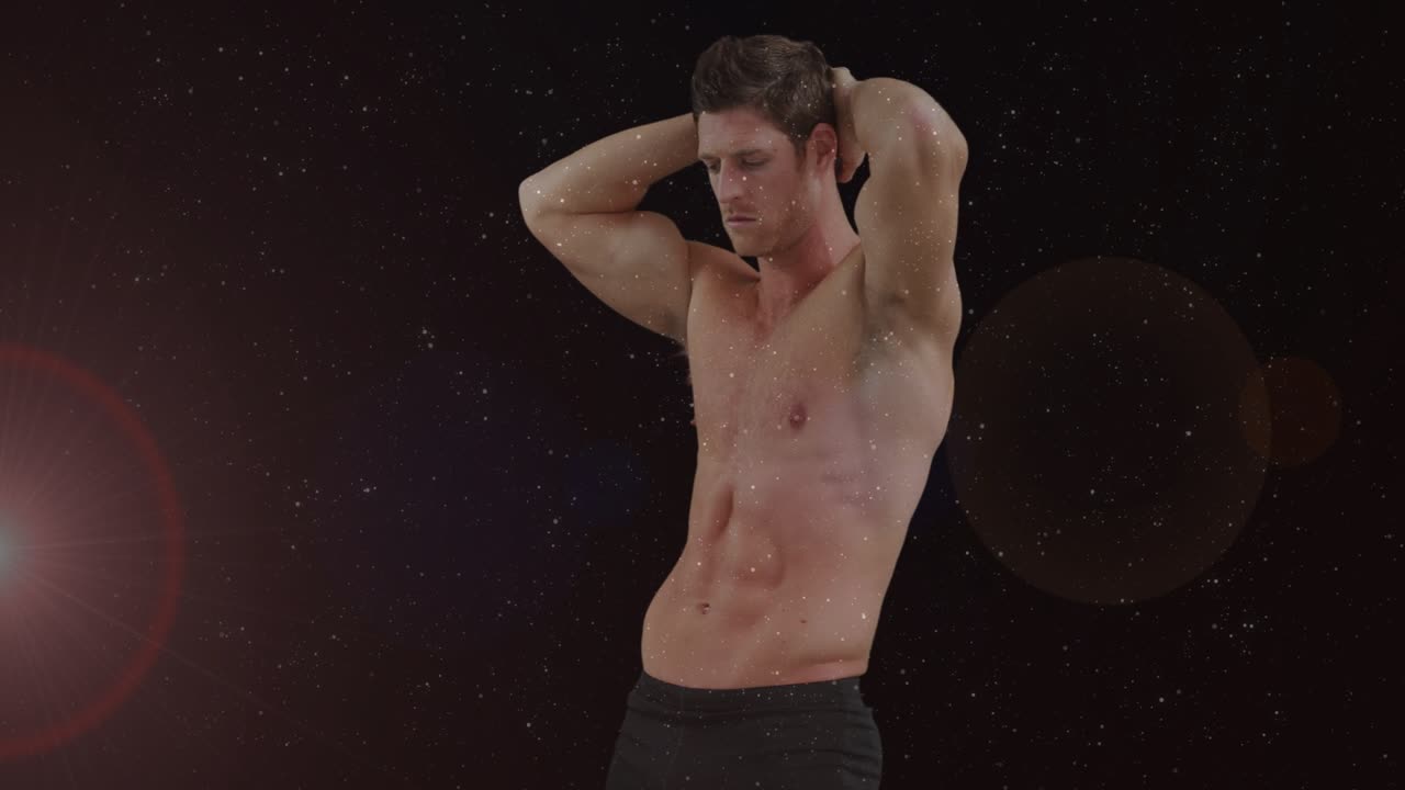 Male fitness model holding studio pose while flare causing subtle shifts and bokeh showing physique