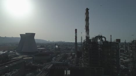 silhouette of a large scale oil refinery with smoke stacks and petroleum storage tanks
