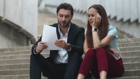 Colleagues-discussing-papers-in-city.-Professionals-talking-about-documents