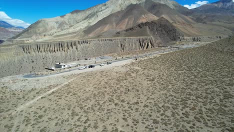 cars parked at top edge of kali gandaki gorge near kagbeni village in mustang region of nepal - aerial parallax