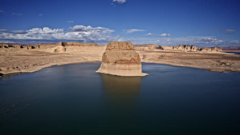 drone footage revealing a striking lone rock in the waters of lake powell, with a stunning desert canyon backdrop.