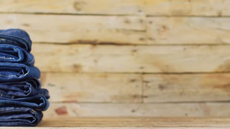 close up of folded jeans with different shades on wooden background with copy space