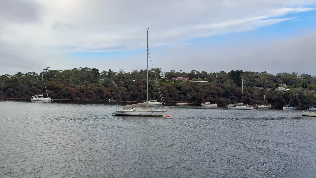 Experience a peaceful ferry journey across the D'Entrecasteaux Channel, departing from the Tasmania mainland towards Bruny Island. Enjoy stunning views of moored boats and picturesque coastal scenery