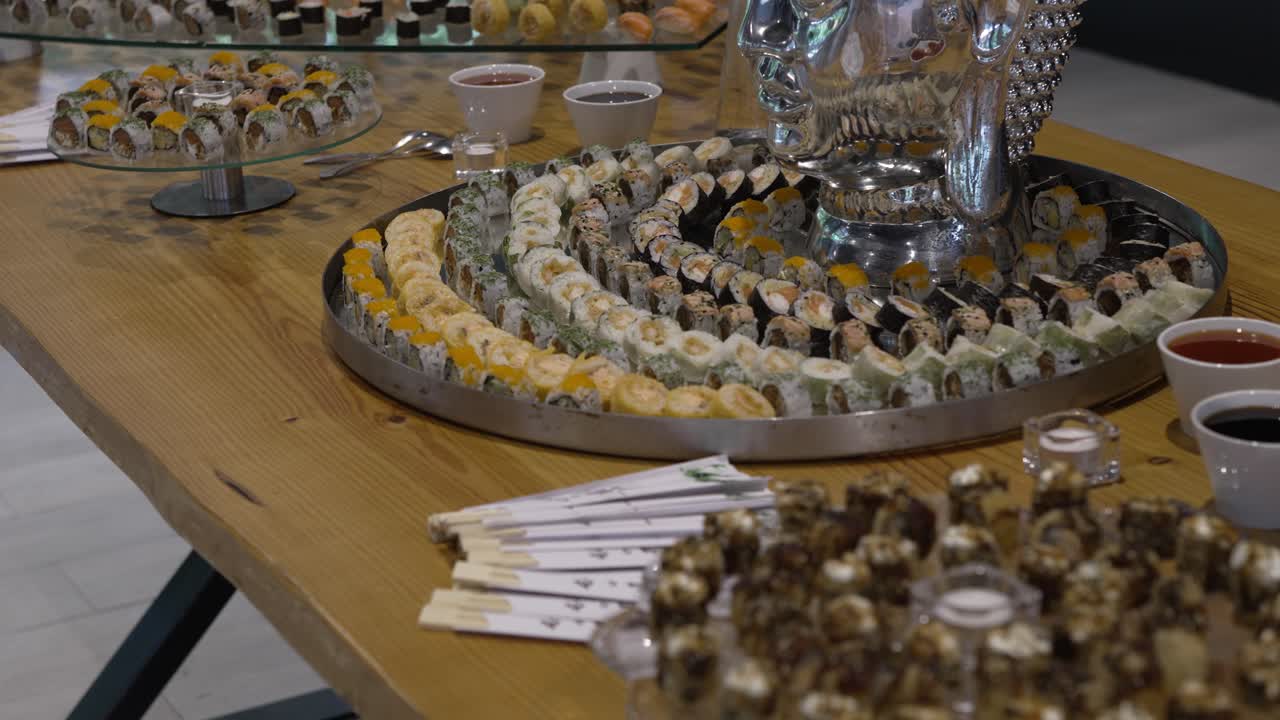 Wedding sushi buffet with assorted rolls, sauces, and artistic decor on a wooden table