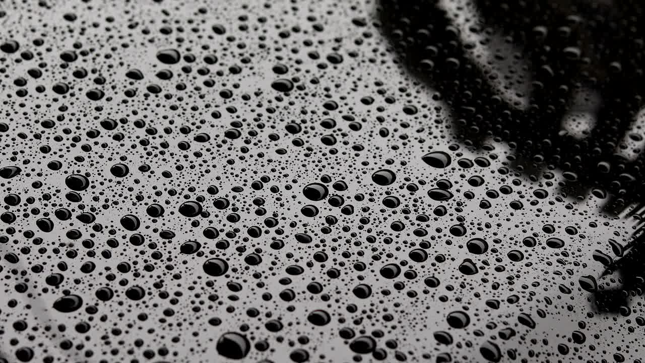 gotas de agua de lluvia en el coche negro