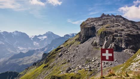 high alpine grass meadow with choss loose gravel with swiss flag on stiff board on sunny day