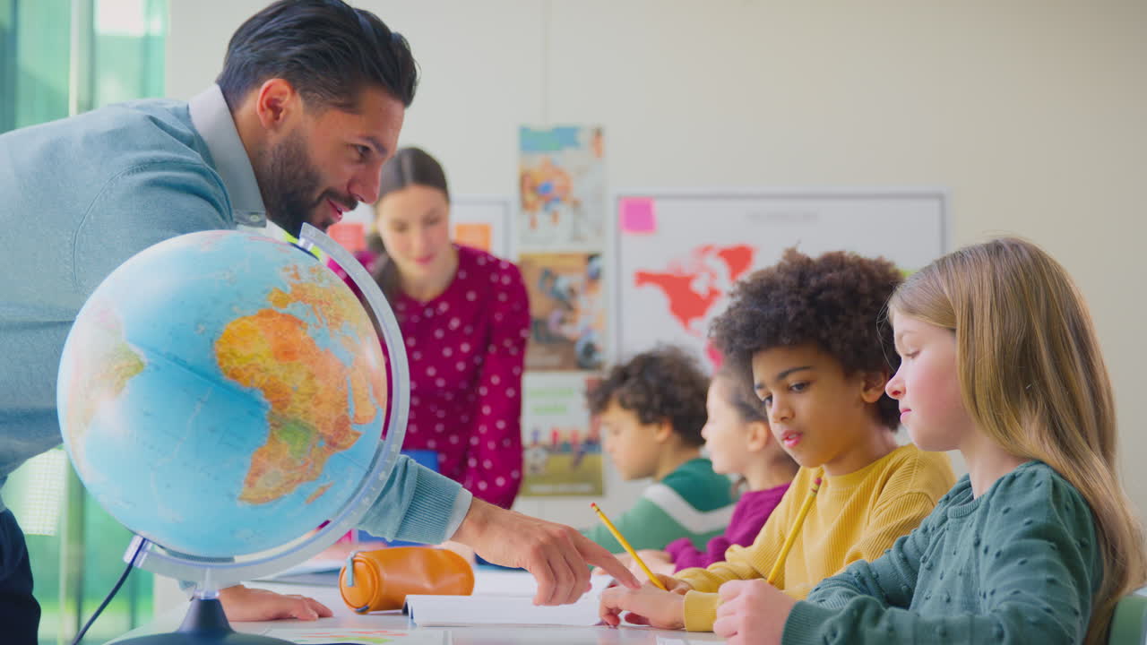 grupo de estudiantes multiculturales con profesores en el aula mirando el globo en la lección de geografía