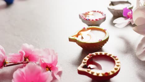 Burning-colourful-candles-celebrating-diwali-with-copy-space-and-flowers-on-white-background