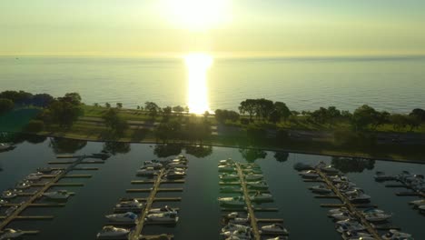 aerial, tracking shot of cars driving on highway with harbor in foreground and water in background