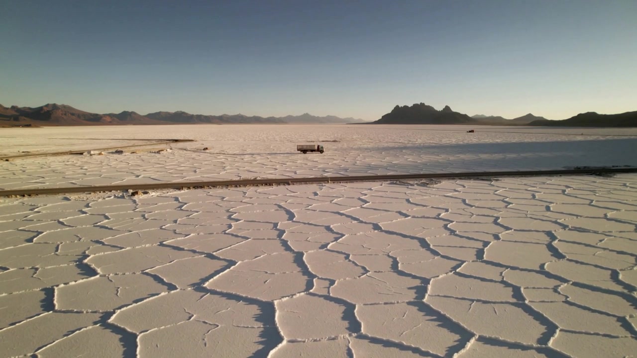 Shot starting, cracked salt plates stretching across salt flat, track providing vehicle scale