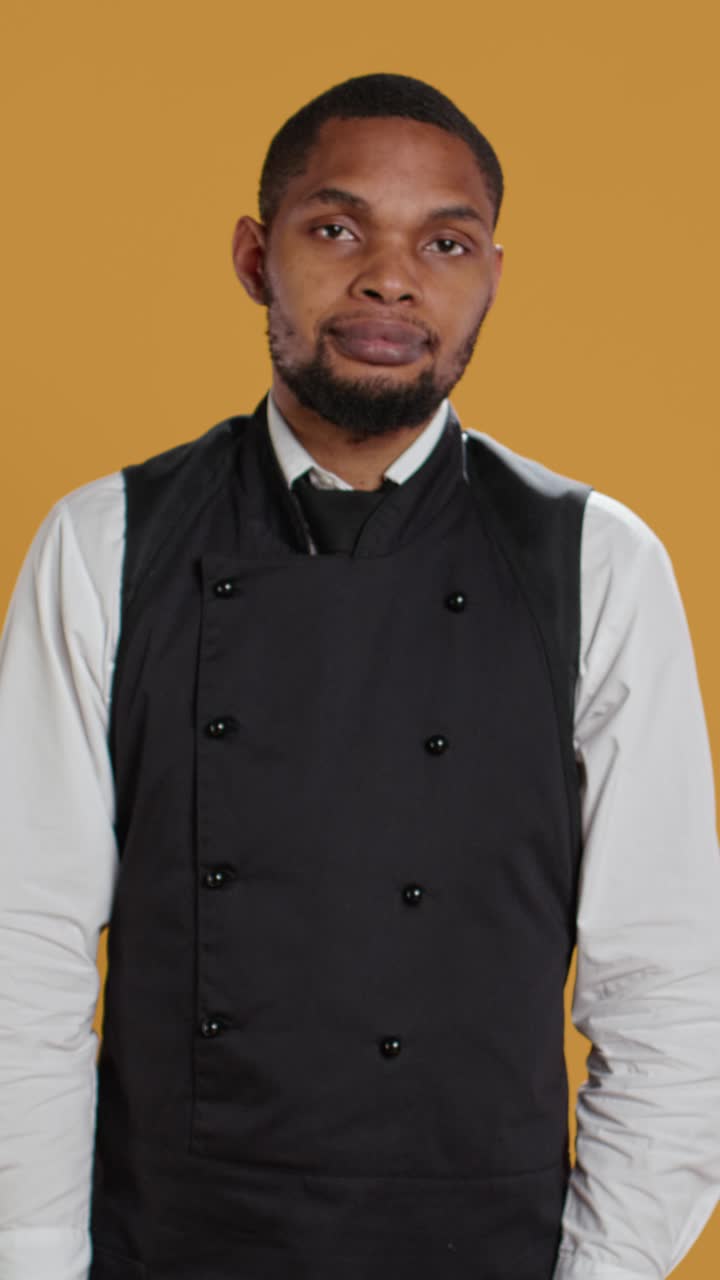 Chef confuso in uniforme che alza le spalle su sfondo giallo