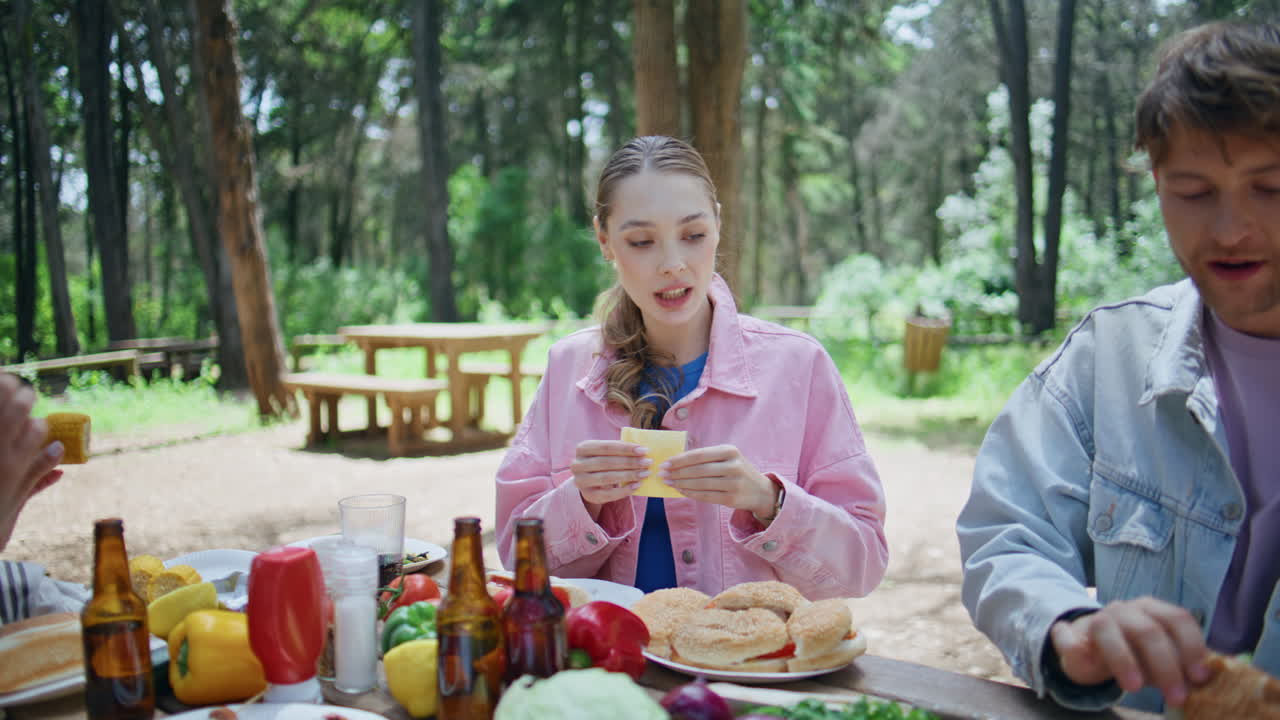 Friendly people eating forest picnic at table closeup. Friends enjoying food