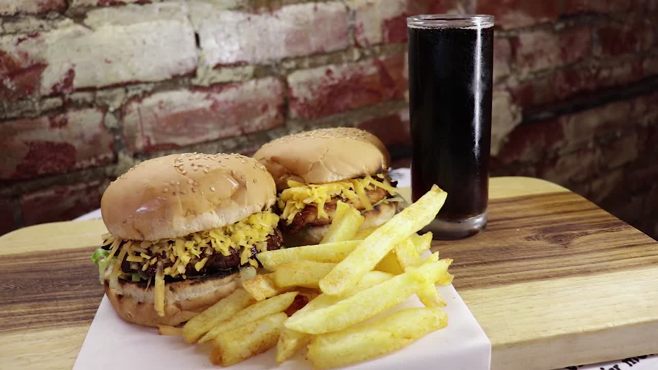 dolly en trago de hamburguesa de ternera y pollo con patatas fritas y refresco en un vaso.