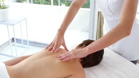 mujer terapeuta masajeando la espalda de su paciente