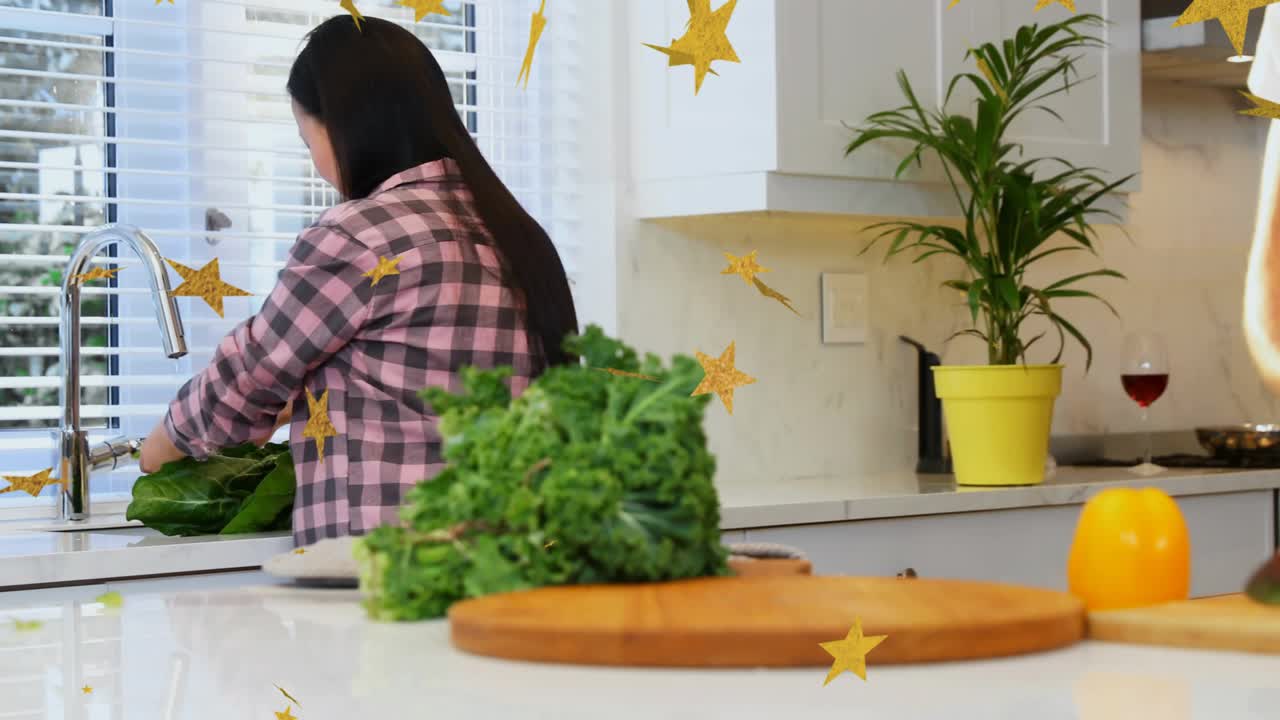 Woman rinsing kale under faucet with golden stars drifting and man chopping carrots for salad