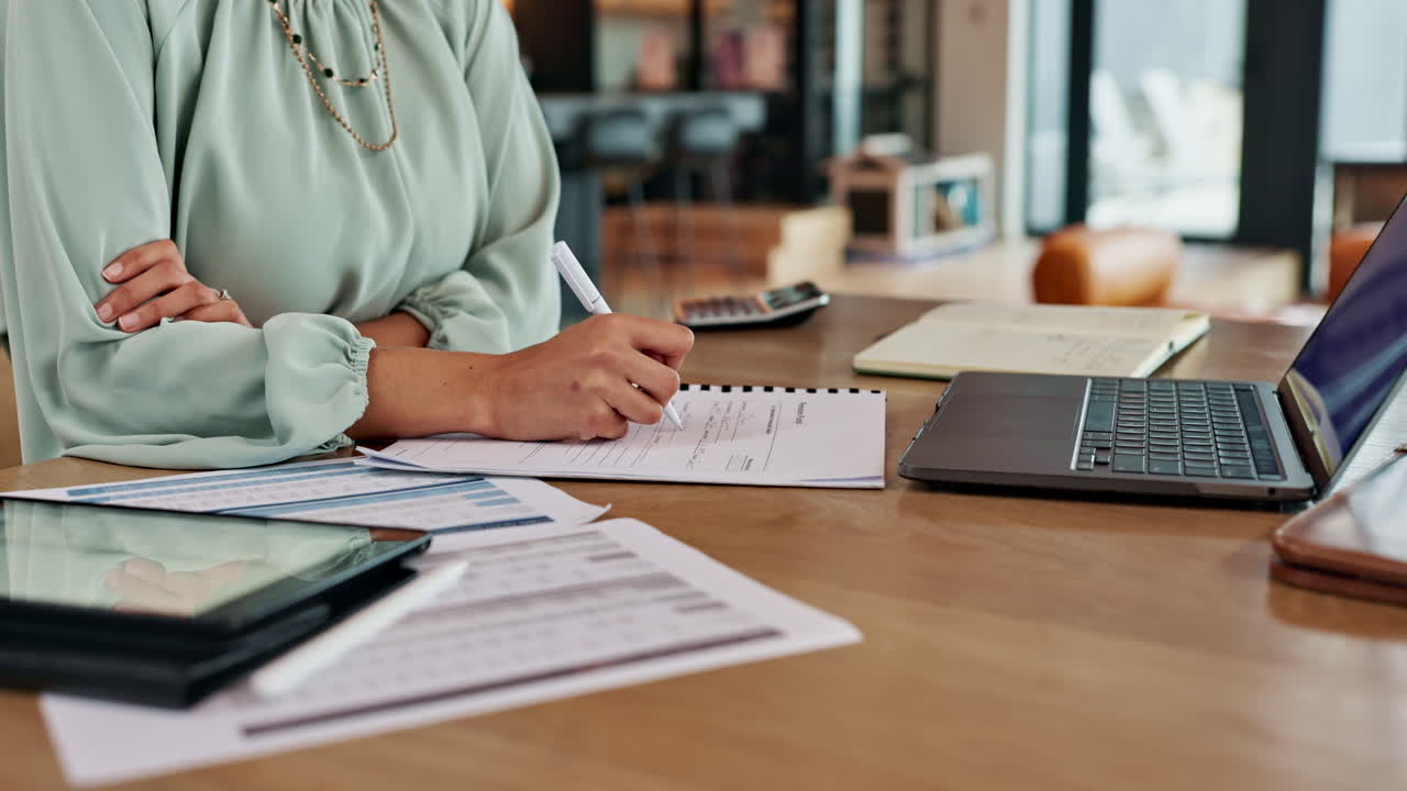 Woman working at desk with laptop and paperwork