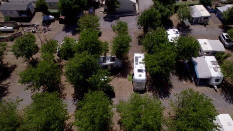 aerial over camping place, parked camping vans among the trees during sunny day, traveling and taking vacation concept