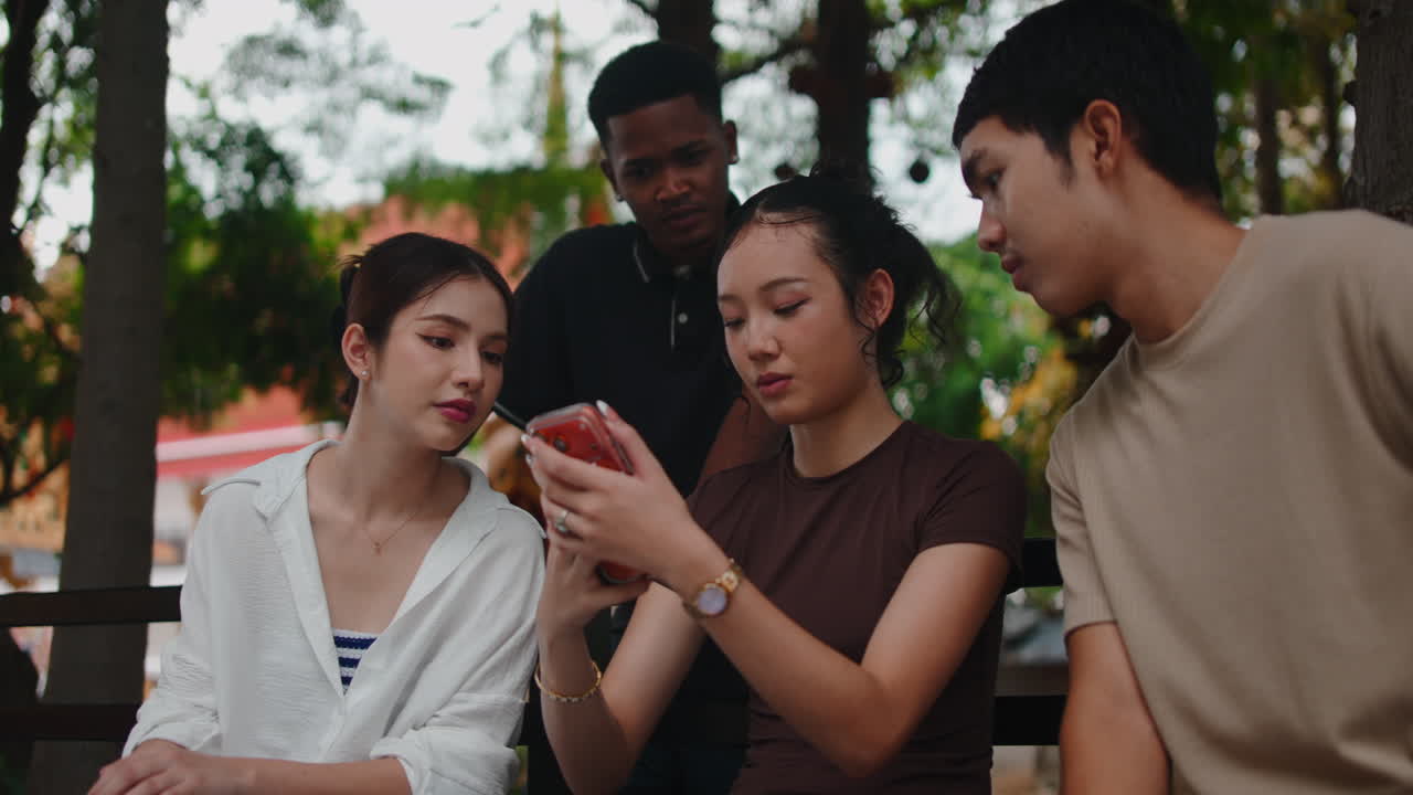 Friends enjoying social media on a smartphone in the park