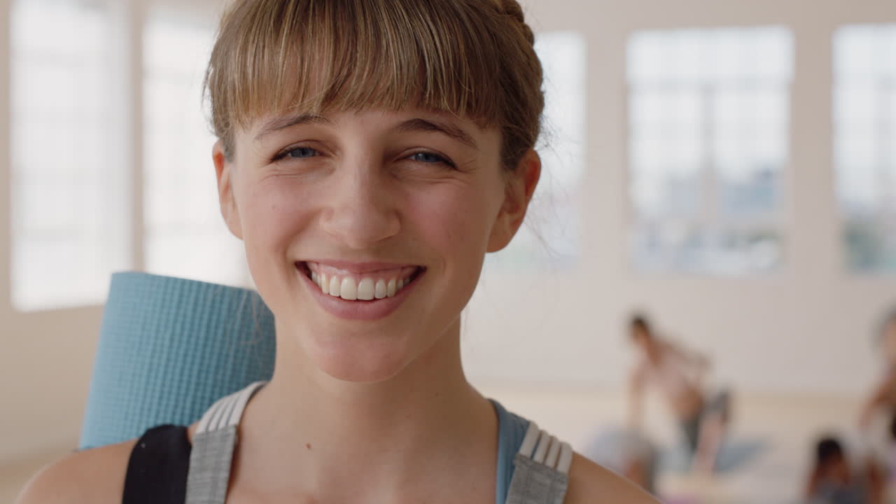 retrato hermosa mujer caucásica de yoga riendo feliz disfrutando de un estilo de vida saludable con gente practicando en el fondo del gimnasio