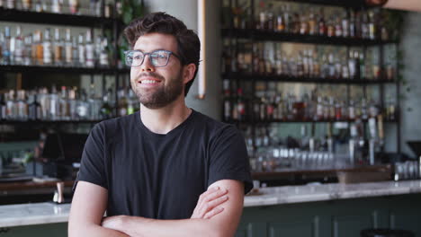 Confident-Male-Owner-Of-Restaurant-Bar-Standing-Inside-By-Counter