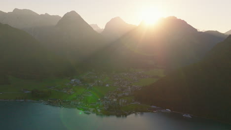 Aerial-view-orbiting-Pretisau-village-at-base-of-sunlit-Austrian-Tyrol-alpine-mountains