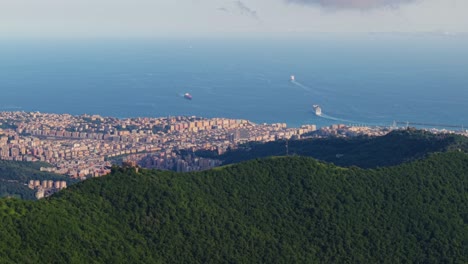 Italy's coastline with city buildings, green hills, and ocean, aerial view