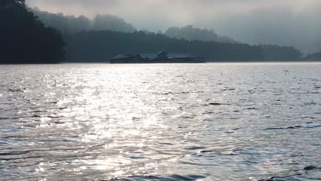 calm river reflecting sunlight, misty mountains in background