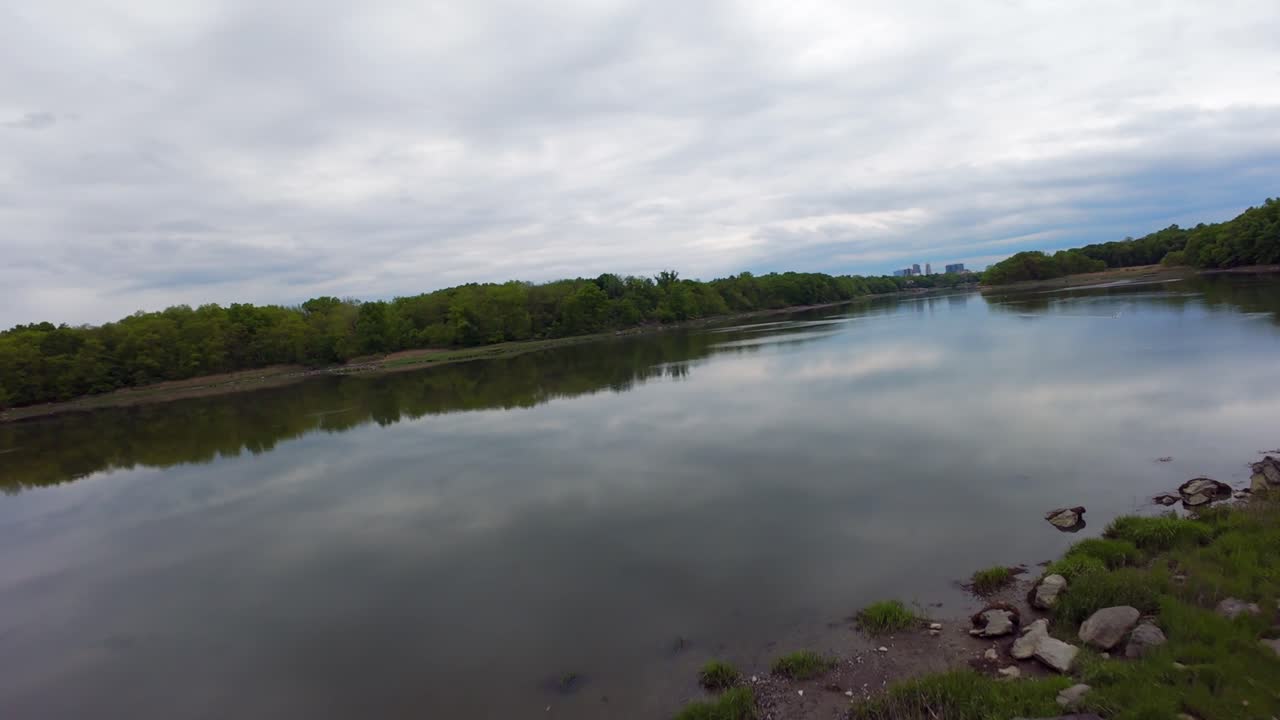 En lavtflyvende FPV-droneudsigt over en lavvandet sø med en reflekterende overflade