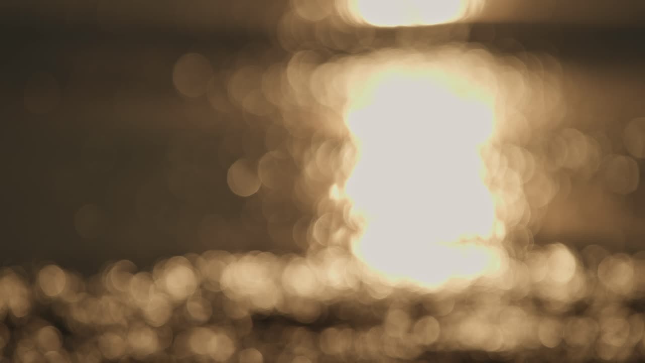 Out of focus shot of shimmering light on the water as ocean waves roll through