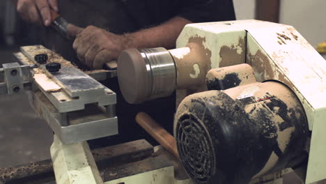 trabajador tallando un disco redondo de madera en un torno con tiro deslizante estabilizado con aserrín