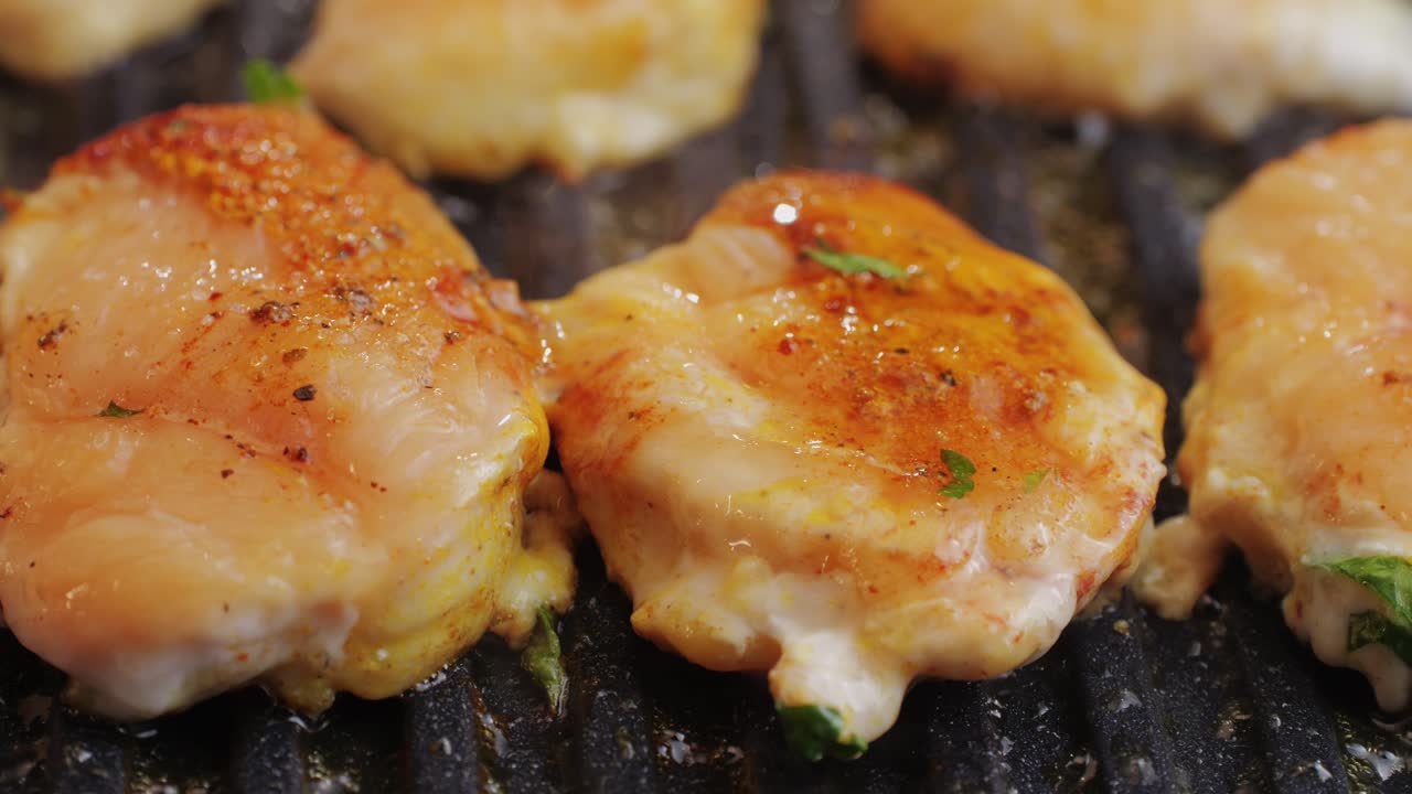 Cooking raw chicken meat in yellow turmeric spice with garlic and greens on grill close-up. Fry chicken slice on frying.pan Grilled chicken, duck, turkey kebab with vegetables.