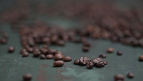 Close-up-pull-out-through-the-coffee-beans-lying-on-the-dark-green-background