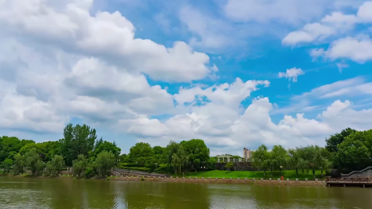 Tranquil Lake with Lush Green Trees Under a Vibrant Blue Sky and Fluffy White Clouds