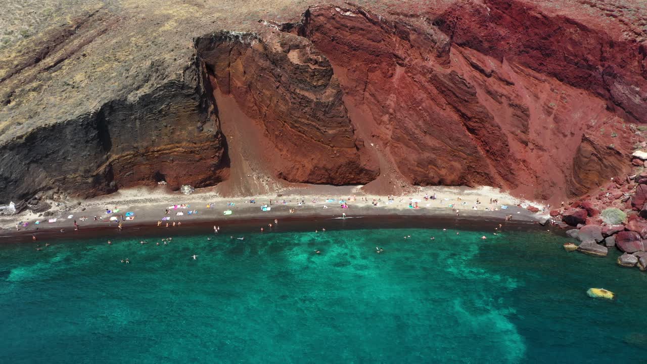 aéreo de arriba hacia abajo que revela la famosa playa roja con agua turquesa y arena roja en santorini, grecia