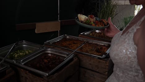 close view of bride in wedding dress putting food on plate at buffet